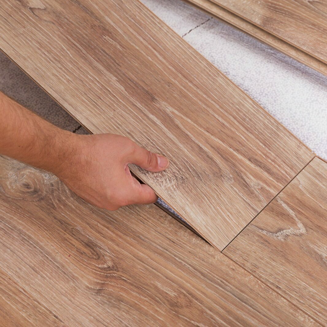 Installing laminate flooring. Carpenter lining parquet boards to each other fitting a plank